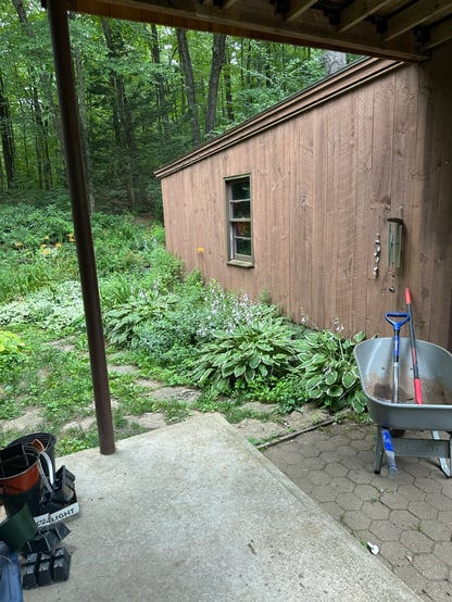 Exterior view adjacent to the home in Hollis, NH, by Blackdog Design/Build/Remodel, showing existing siding, garden area, and patio space prior to renovation.