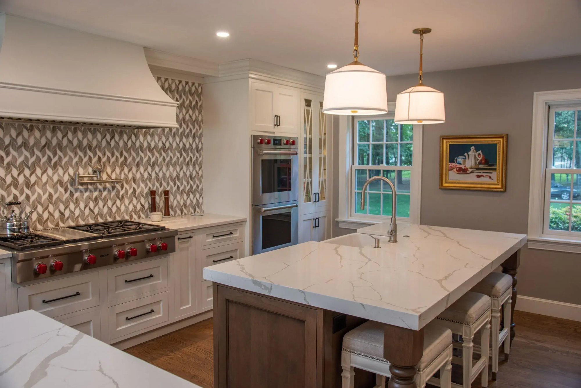 kitchen remodel with oversized white marble island and oversized white hood and luxury range