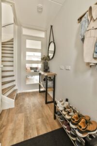 Remodeled entryway with light wood floors, white walls, slightly curved staircase to the left, and heated flooring.