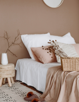 Remodeled bedroom with white bedsheets and light wood nightstand and wall painted in Little Greene’s Mochi color.