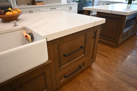 A redesigned kitchen island with a farmhouse kitchen sink and quartz countertops.