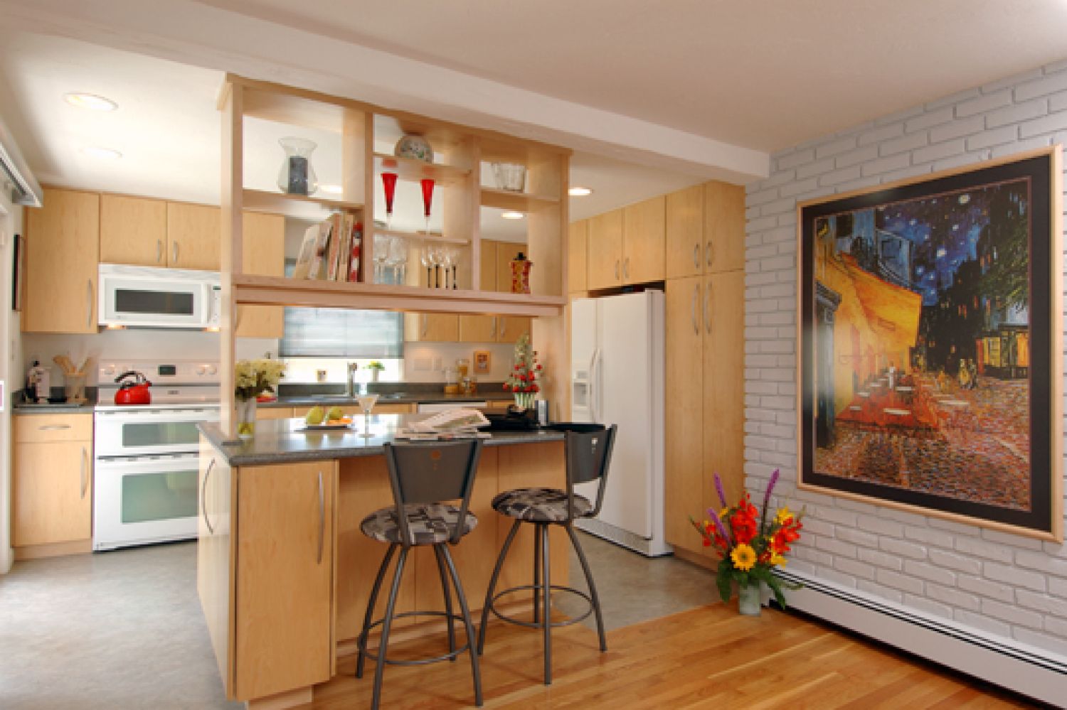 Small kitchen remodel with light wood cabinets, small island with open shelving above, two stools, and light tile floor.