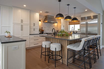 Finished kitchen remodel in Andover, MA by Blackdog Design/Build/Remodel featuring white shaker cabinets, a large square center island with seating, black pendant lights, and stainless steel appliances