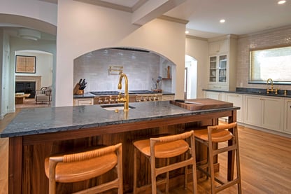 Countertop seating at a large center island overlooking a prep sink and stainless steel range underneath a custom archway in a kitchen remodel by Blackdog Design/Build/Remodel in Andover, MA