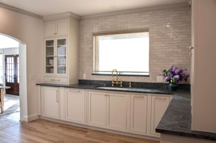 A farmhouse style sink sits beneath a large window and subway tile backsplash in a kitchen remodel in Andover, MA by Blackdog Design/Build/Remodel.