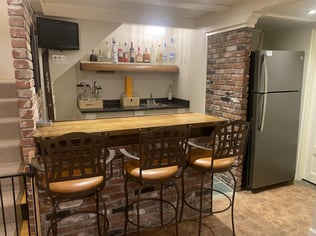 brick kitchentte and narrow fridge with bar stools and narrow island