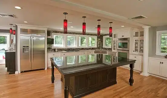 Kitchen upgrade with large black island, red light fixtures, and windows across backsplash wall