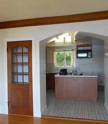 vintage home with dark hardwood and an archway leading to the kitchen