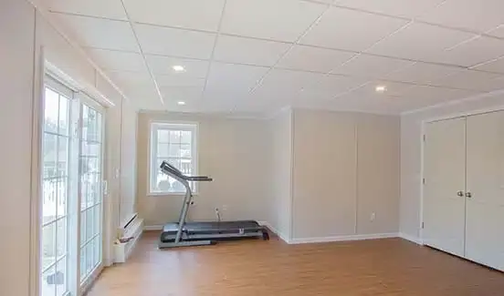 Bright open-plan basement remodel with leather couches, ping pong table, and projector screen