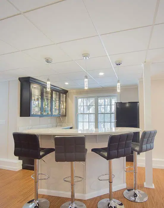 Bright open-plan basement remodel with leather couches, ping pong table, and projector screen