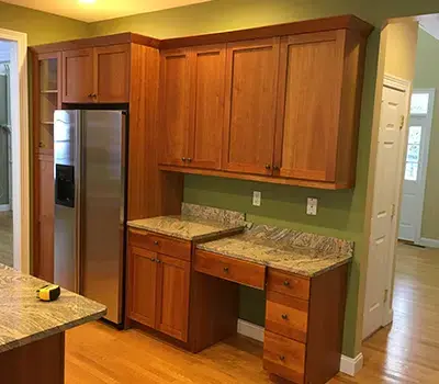 Kitchen with light brown cabinets, green walls, and silver refrigerator