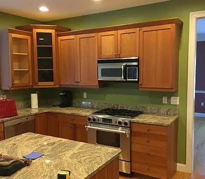 Kitchen with light brown cabinets, green walls, and silver refrigerator