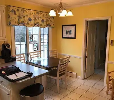 Older kitchen with traditional, white cabinets and dark appliances
