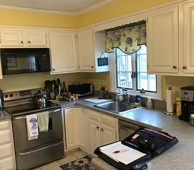 Older kitchen with traditional, white cabinets and dark appliances