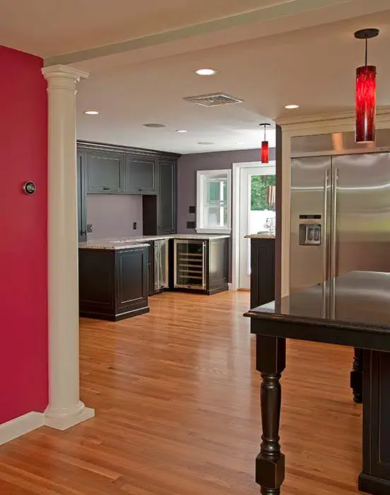Kitchen upgrade with large black island, red light fixtures, and windows across backsplash wall