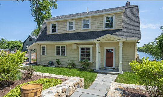 Big yellow home with a deep red door and nice green landscaping