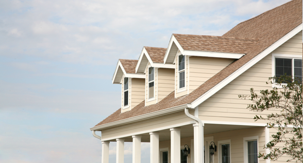 A yellow-beige Cape Cod style home with covered porch and three dormers across front of roof.